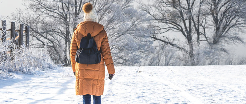 Woman walking in snow with mobile game in pocket